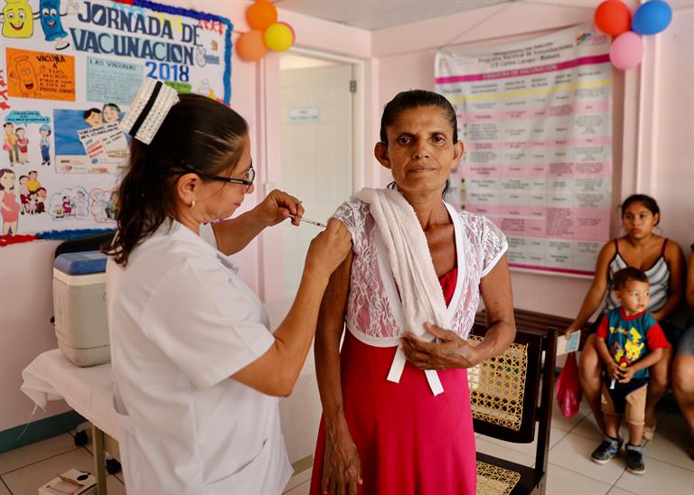 A nurse injects vaccine into an elderly woman's shoulder, in Nicaragua