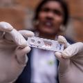 A health worker shows the positive result from a malaria RDT carried out during the patient’s follow-up home visit