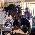At the public Manhiça District Hospital, an intake nurse examines a baby for malaria symptoms in the triage room