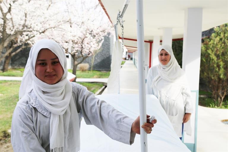 Two nurses in white uniforms at hospital garden in Afghanistan