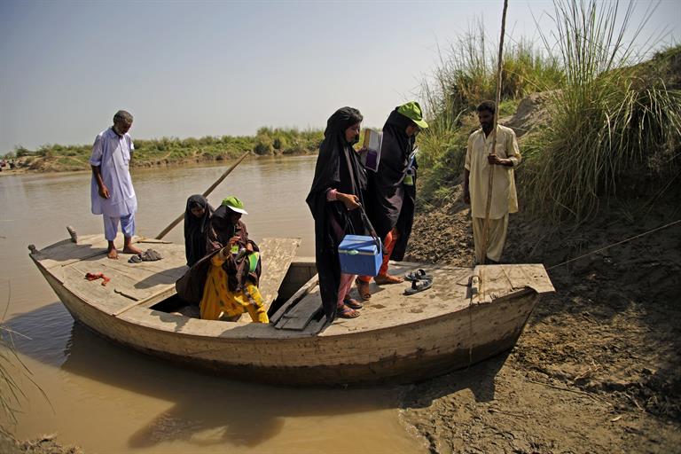 A group of female vaccination volunteers get off a boat on the Indus River in Pakistan