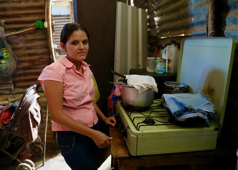 A woman in her kitchen, in front of stove, in Comarca Bodque de Xiloa, Nicaragua