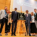 Rwandan President, Paul Kagame and WHO Director-General, Dr Tedros with family of Urbani, standing around a plaque
